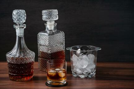 Two crystal whisky decanters, a glass and a container with ice cubes. 